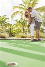 Caucasian couple playing miniature golf