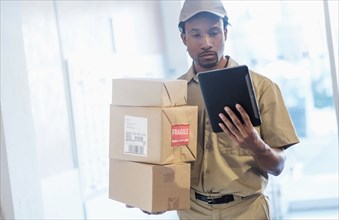 Black delivery man using digital tablet