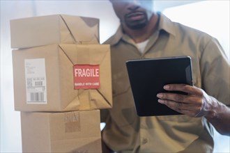Black delivery man using digital tablet