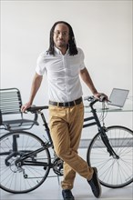 Black businessman with bicycle in office