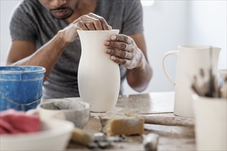 Black artist shaping ceramic vase in studio