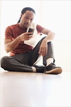 Black man using cell phone on floor