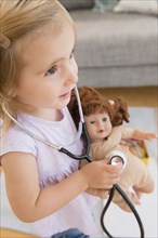 Caucasian girl playing doctor with doll