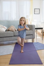 Caucasian girl practicing yoga in living room