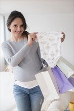 Pregnant Caucasian woman shopping for baby clothing