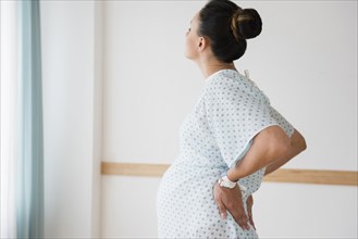 Pregnant Caucasian with back pain in hospital gown