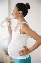 Pregnant Caucasian woman drinking water bottle