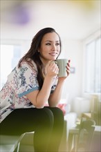 Woman drinking cup of coffee in living room