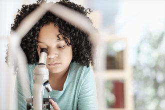 African American girl using microscope in science classroom