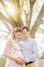 Pregnant Caucasian couple hugging outdoors