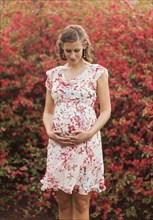 Pregnant Caucasian woman holding her belly outdoors