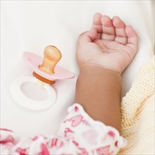 Hand of African baby and pacifier