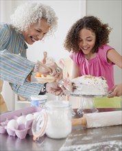 Grandmother and granddaughter frosting cake