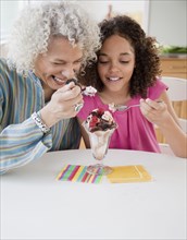 Grandmother and granddaughter sharing ice cream sundae