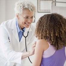 Doctor checking girl's heart with stethoscope