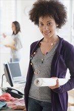 Mixed race woman holding blueprints in office