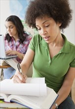 Mixed race woman taking notes in college classroom