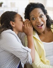 Daughter whispering secret to mother