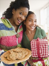 Mother and daughter carrying birthday gift and cookies