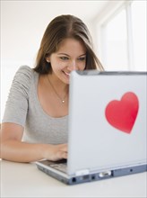Indian woman using laptop with heart-shaped sticker
