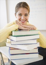 Smiling Indian student leaning on stack of textbooks