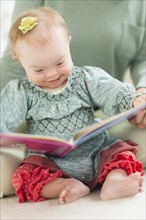 Caucasian baby girl with Down Syndrome reading