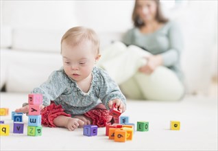 Caucasian baby girl with Down Syndrome playing with blocks