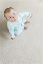 Caucasian baby girl with Down Syndrome sitting on floor