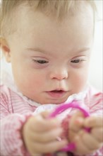 Caucasian baby girl with Down Syndrome playing with ring