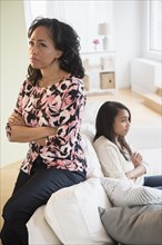 Frustrated mother and daughter sitting on sofa