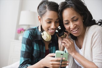 Mother and daughter listening to cell phone music on headphones