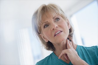 Older Caucasian woman checking pulse on neck