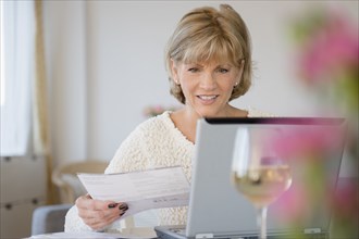 Older Caucasian woman paying bills using laptop