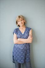 Confident older Caucasian woman standing at wall