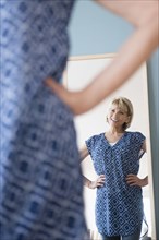 Older Caucasian woman admiring dress in mirror