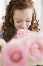 Caucasian woman smelling pink rose