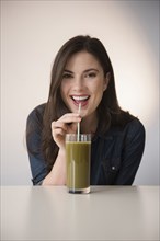 Caucasian woman drinking green smoothie with straw