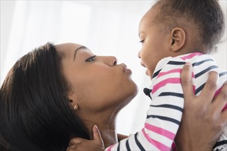 Black mother lifting baby daughter face to face
