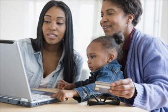 Black multi-generation family online shopping using laptop