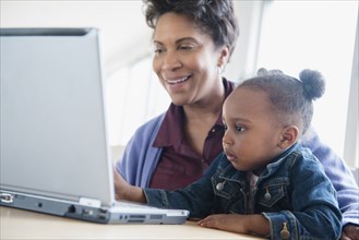 Black grandmother and granddaughter using laptop