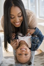 Black mother holding baby daughter upside-down