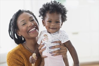 Smiling Black mother holding baby daughter