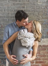 Caucasian man hugging and kissing expectant mother