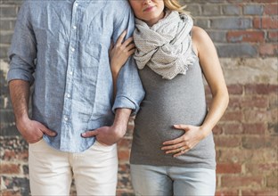 Smiling Caucasian expectant mother holding arm of man