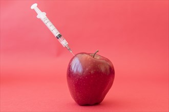 Syringe injecting red apple