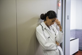 Stressed Indian doctor leaning on wall