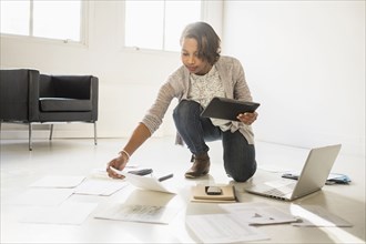 Black businesswoman using laptop and digital tablet on floor