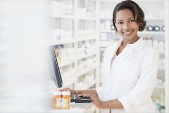 Smiling Black pharmacist using computer