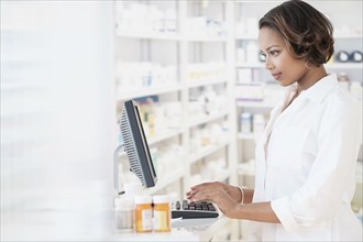 Smiling Black pharmacist using computer
