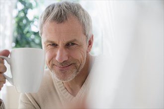 Older Caucasian man holding coffee cup